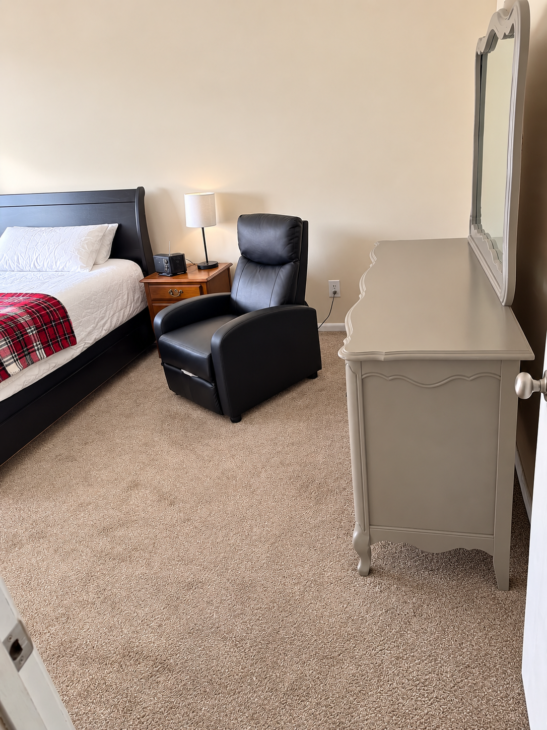 Furnished bedroom with bed, recliner and dresser